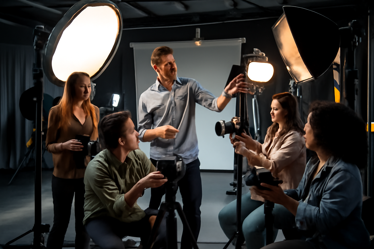 کلاس عملی عکاسی در استودیو با حضور استاد و دانشجویانی که در حال تمرین با دوربین‌ها و تجهیزات نورپردازی حرفه‌ای هستند. محیط استودیو با نورپردازی مناسب و فضای ساده طراحی شده است.