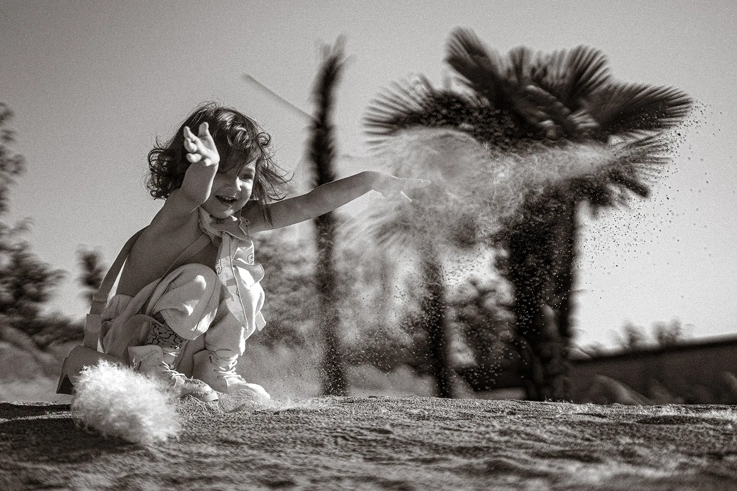 کودک در حال پاشیدن شن و خاک